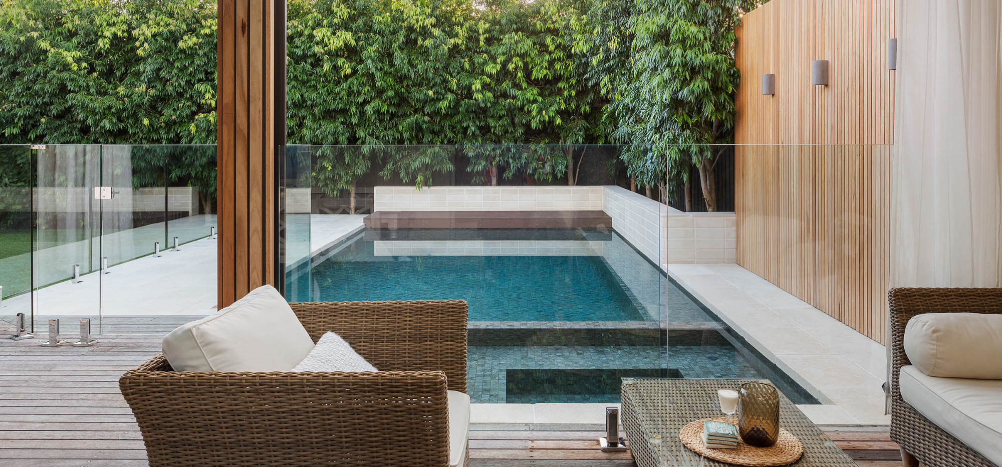 Modern outdoor patio with pool, chairs, and table, showcasing a stylish and inviting residential pool area.